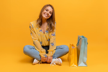 beautiful attractive smiling woman in yellow shirt and jeans with shopping bags