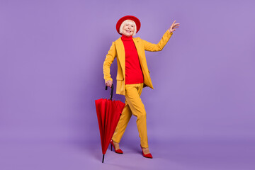 Full body photo of cheerful short hairdo senior lady wear yellow suit cap umbrella isolated on purple background