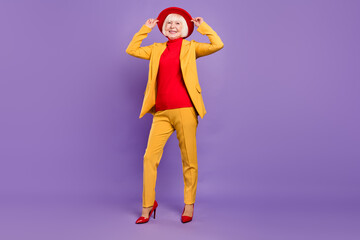 Full length photo of cheerful nice short hairdo aged lady wear yellow suit cap isolated on purple color background