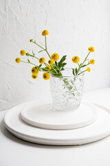White home decoration with yellow flowers, ceramic vase and glass on tray