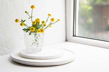 White home decoration with yellow flowers, ceramic vase and glass on tray