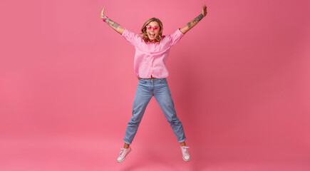 blond pretty woman in pink shirt and jeans smiling jumping