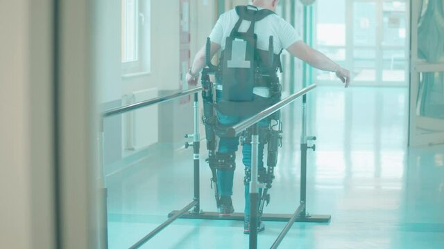 A man is practicing walking in the exoskeleton in a medical facility