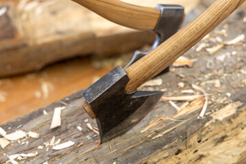 Carpentry concept. The axes are driven into a wooden log. Works in a carpentry workshop