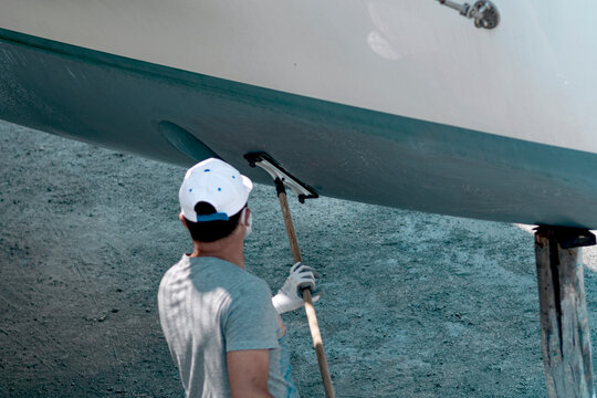 Man cleaning sailing boat hull on docks