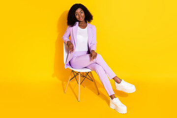 Full size photo of young happy smiling confident afro businesswoman sit chair isolated on yellow...