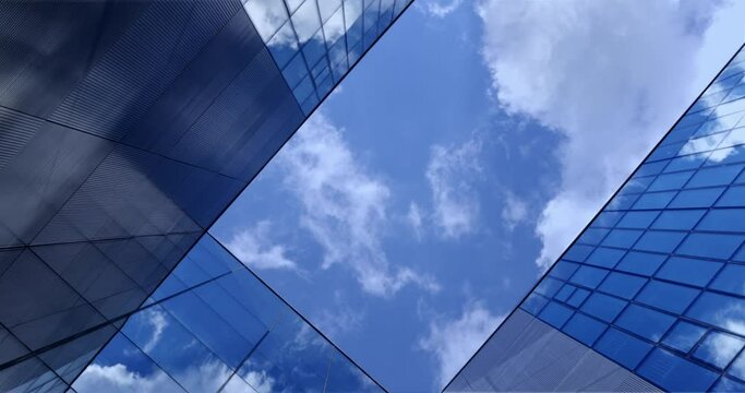 Up view between glass metal office buildings, business skyscrapers, moving clouds sky. Looking up at modern downtown financial office building architecture. Business, finance, real estate 4K footage