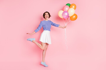 Full size photo of young attractive smiling happy excited cute girl hold balloons raise leg isolated on pink color background