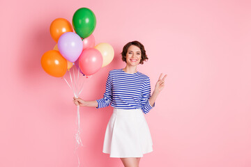 Photo of young attractive cheerful smiling positive girl hold balloons showing v-sign isolated on pink color background