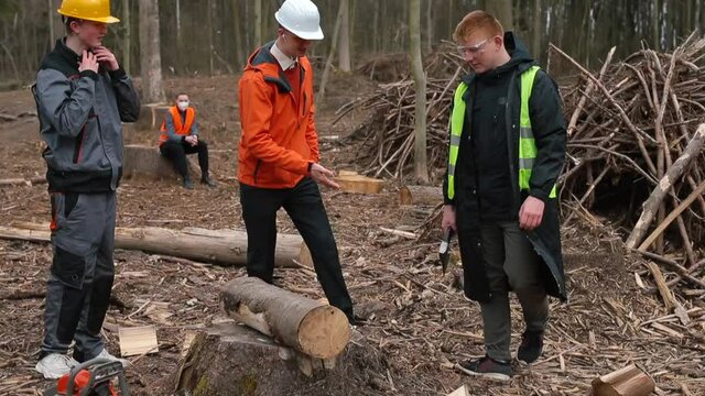Portrait of a group of sawmill workers. The assistant holds the log on his shoulder, the manager of the chainsaw. Successful team at work. Willingness to get the job done.