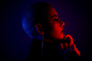 Portrait of beautiful young woman with short hair wearing glasses in neon light