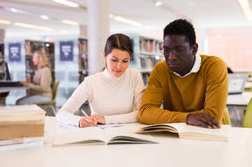 Fototapeta premium Portrait of couple of adult students studying together in public library. High quality photo