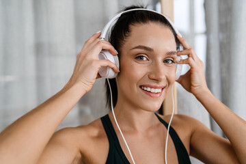 White brunette woman smiling and listening music with headphones
