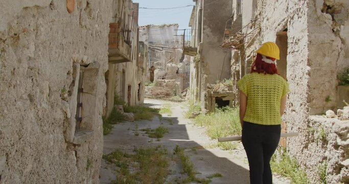 Giovane ragazza ingegnere con caschetto giallo visita la citt&agrave; distrutta dalla guerra