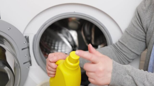 Female hand takes clothes from laundry machine. Loading washing machine. Preparing laundry washing