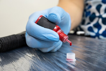 The process of preparing tools for permanent makeup. Master's hands in blue gloves.