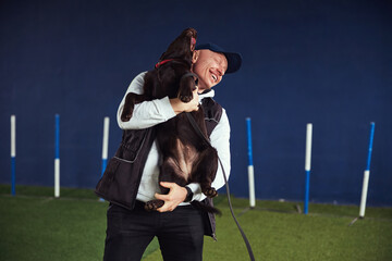 Fototapeta premium Merry instructor and a Chocolate Labrador Retriever in his arms