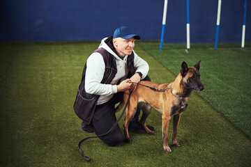 Instructor seated on the synthetic turf next to a dog