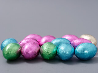 chocolate candies in foil in the form of Easter eggs on a gray background