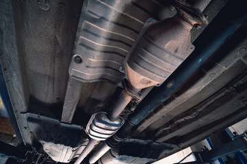 Vehicle underbody exhaust pipe, catalyst, resonator, exhaust system. Old parts require repair and replacement. Car service and maintenance. cardan and outboard bearing - obrazy, fototapety, plakaty
