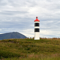Lighthouse with a red top, close to the Atlantic Ocean Road in Norway © Barnabas Davoti/Wirestock