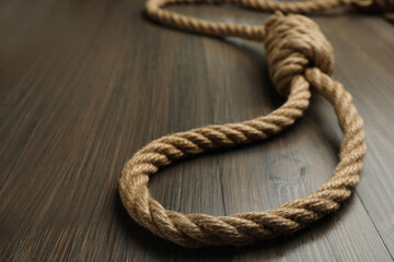 Rope noose on wooden table, closeup. Space for text