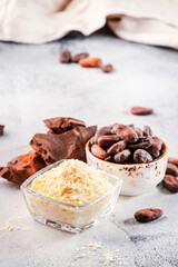 Organic cocoa butter bowl, beans, grated lump on gray table. Copy space