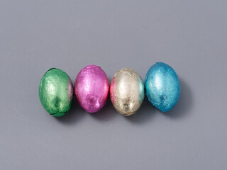 chocolate candies in foil in the form of Easter eggs on a gray background