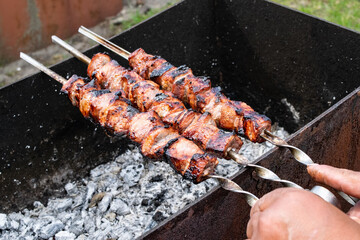 Meat skewers grill. Pork or beef are fried on open fire. Barbecue kitchen party close up image. Kebab or shashlik cooking on spits