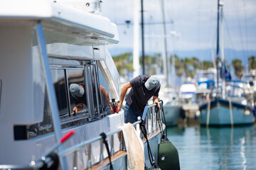 maintenance worker cleaning a yacht docked on the dock