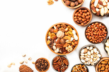 Nuts in bowls set. Cashews, hazelnuts, walnuts, pistachios etc. Healthy food snack mix on white table, top view