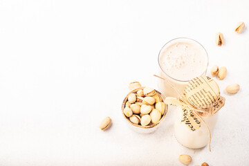 Fototapeta na wymiar Pistachio nut milk in glass on grey table. Non dairy alternative vegan milk. Healthy diet food and drink. Copy space, top view