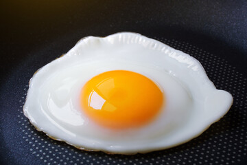Close-up of, Fried egg and Fresh yolk yellow uncooked in pan background, Morning food preparation or Breakfast with non stick kitchenware and oil free for Healthy food and Health care concept.