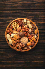 Nuts in bowls. Walnuts, pistachios, pecans, macadamia, almonds and other. Healthy food snacks mix on wooden background, top view