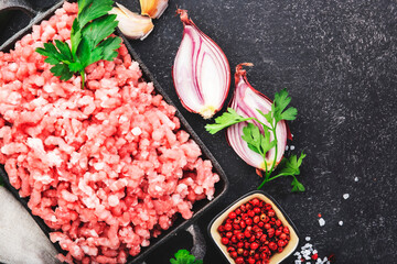 Mince, ground minced pork, beef meat with ingredients for cooking on black background. Top view, copy space