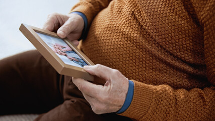close up view of senior male hands gently holding family picture on grey background.