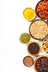 Set of superfoods, legumes, cereals, nuts, seeds in bowls on white background. Superfood as chia, spirulina, beans, goji berries, quinoa, turmeric and other. Copy space, top view