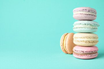 Delicious colorful macarons on turquoise background. Space for text