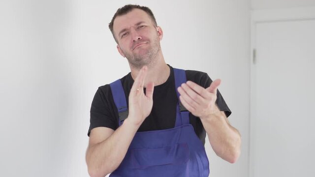 Close-up, a male plumber claps his hands and crosses his arms on his chest.