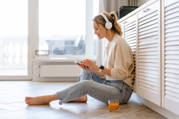 Young woman smiling while listening music with cellphone and headphones