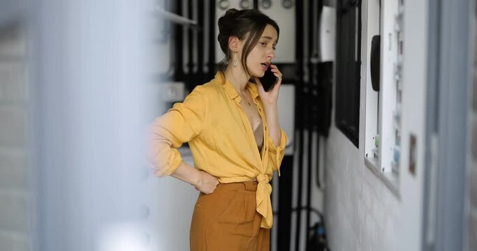 Confused woman having problems with electricity at home, speaks on the phone trying to solve the problem. Concept of female incompetence in home electricity