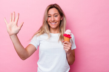 Young australian woman holding an ice cream isolated on pink background smiling cheerful showing number five with fingers.