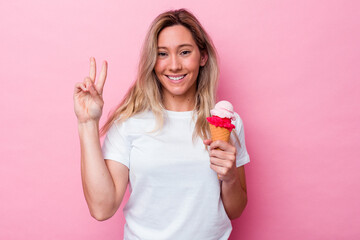 Young australian woman holding an ice cream isolated on pink background showing number two with fingers.