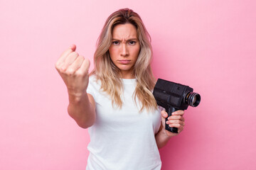 Young australian woman filming with a vintage video camera isolated showing fist to camera,...