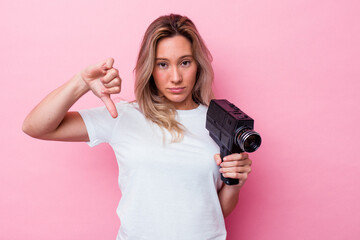 Young australian woman filming with a vintage video camera isolated showing a dislike gesture,...