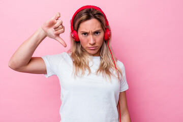 Young australian woman listening music isolated on pink background showing a dislike gesture, thumbs down. Disagreement concept.