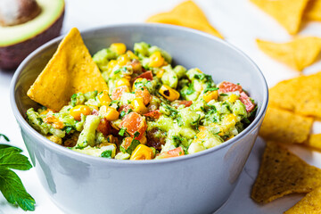 Avocado dip guacamole with grilled corn in gray bowl. Vegan food concept, Mexican cuisine.