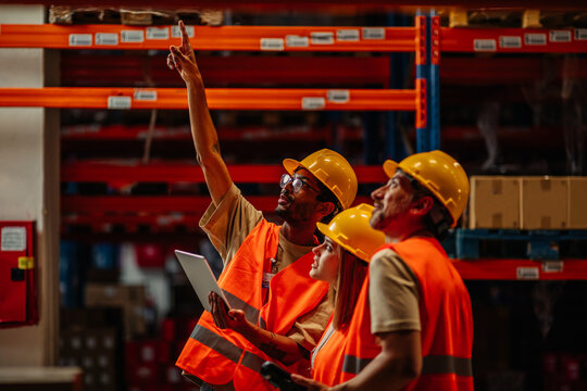 Manager with coworkers controlling stock in factory warehouse