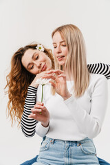 Young two women hugging while holding flower and pulling out petals