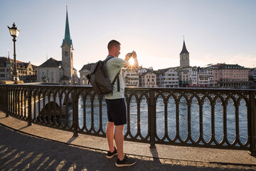 Man photographing cityscape of old town at beautiful sunset. Zurich, Switzerland.